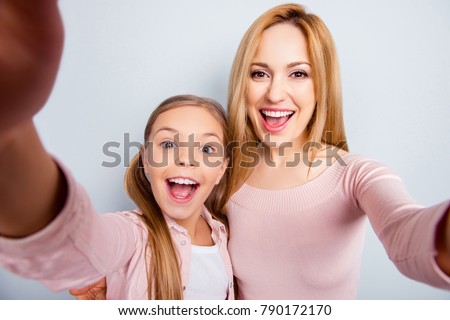Self portrait of crazy, foolish mother and daughter with open mouth, laughing, together making selfie on mobile phone over gray background, spending, celebrate happy woman's day Royalty-Free Stock Photo #790172170
