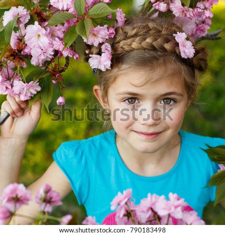 Portrait of a beautiful young girl in blossom cherry garden. Adorable little child play in spring park. Cute kid walk with family on holidays