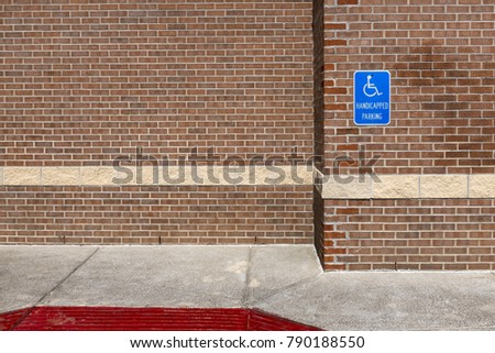Blue handicapped parking sign on a red brick wall of an office building in the United Sates of America; Concept for parking for disabled people