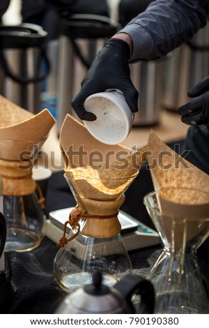 Barista preparing cold brew coffee in glass coffee makers with wood collar