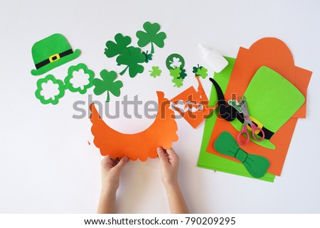 Top view.  Children's hands cut out a mask from paper for a St. Patrick's Day