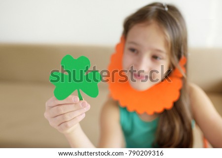 The girl cuts out clover leaves from paper for a St. Patrick's Day