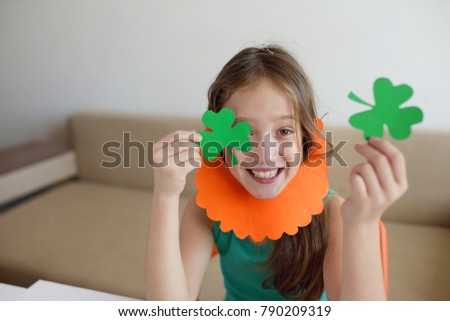 The girl cuts out clover leaves from paper for a St. Patrick's Day