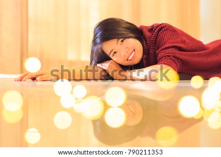 Asian woman indoor portrait lying down on the floor with warm light background, selected focus