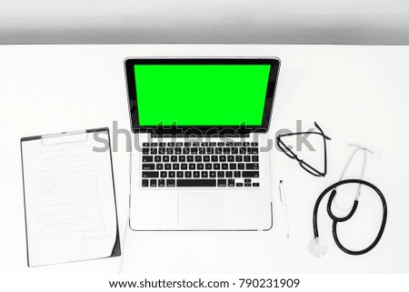 Top view doctor working hard at desk with green screen laptop equipment.