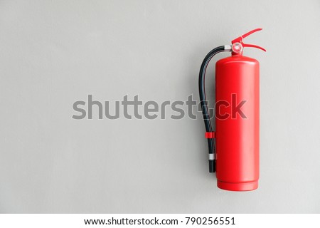 Fire extinguisher on the gray wall Royalty-Free Stock Photo #790256551
