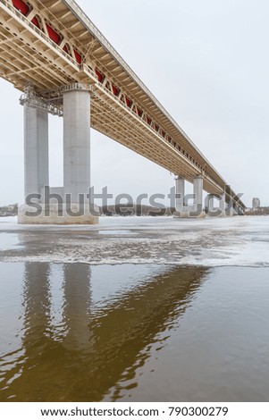 Bridge in reflection in a frozen river at winter
