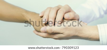 Two people holding hands for comfort. Doctor consoling relatives of patients in hospital concept banner panoramic crop for copy space.