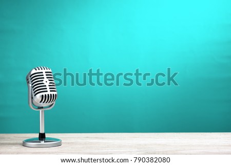 Retro microphone on wooden table with turquoise wall background Royalty-Free Stock Photo #790382080