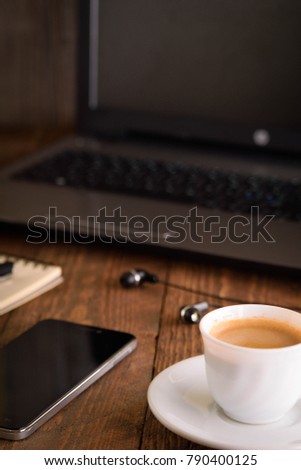 
Laptop (notebook) mobile phone (smartphone) and notepad with pen on old wooden table.
Work place modern.Cup of coffee