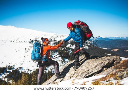 Climber helping teammate climb, the man with the backpack reached out a helping hand to his friend. Royalty-Free Stock Photo #790409257