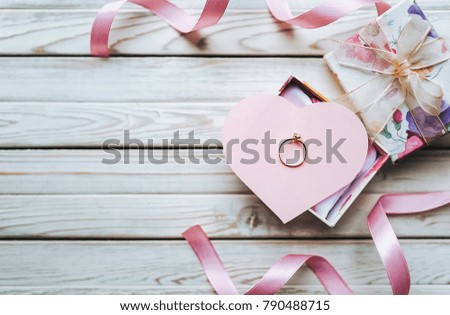Marriage proposal concept. A wedding ring in a gift box on a wooden background. Valentine's Day. Copy space.
