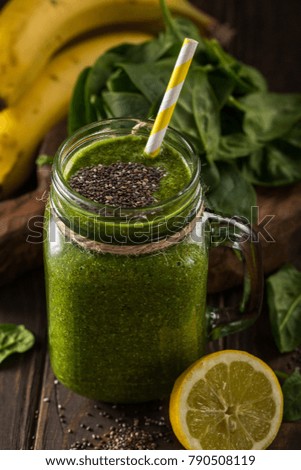 Healthy breakfast with green smoothie in glass jar and ingredients. Detox, diet, healthy, vegetarian food concept. Dark photo, high angle view.