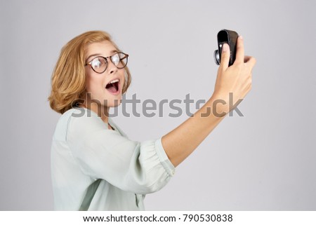   A woman in glasses looks at the camera on a light background, Selfie                             