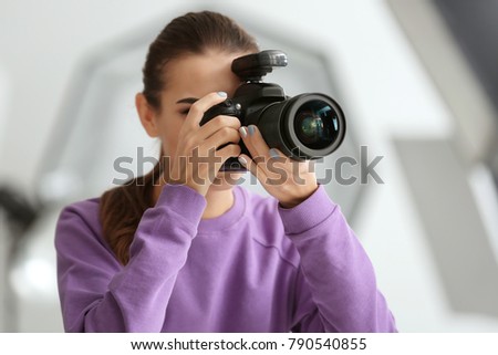 Beautiful young photographer taking photo in professional studio