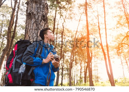 Traveler man with vintage camera taking photo in the forest