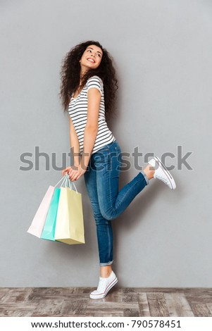 Studio shot of smiling woman feeling pleasure and joy, after buying lots of goods or presents in shopping mall 
