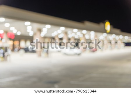 Blurred gas station in Madisonville, Texas, US at night. Defocused, out of focus gas station and convenience store, car drive in and out. Abstract petrol station, industrial background with copy space