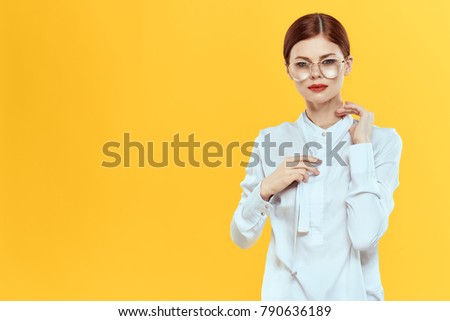 beautiful woman in glasses, in a white shirt on a yellow background                               