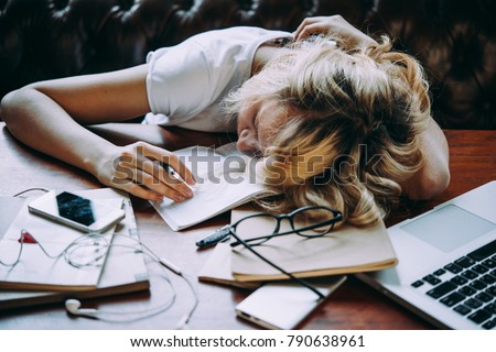A tired teenage girl sleeping on her table while doing her school homework. Laziness and procrastination concept Royalty-Free Stock Photo #790638961