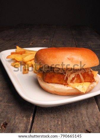 Fish burger with French fries on a white plate