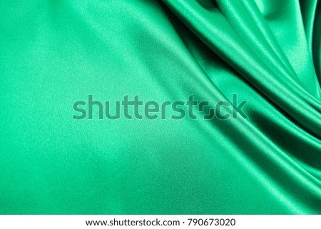 Smooth elegant green color silk or satin luxury cloth fabric texture, abstract background design.