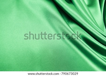 Smooth elegant green color silk or satin luxury cloth fabric texture, abstract background design.