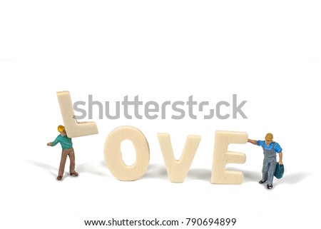 selective focus of miniature worker holding wood text love,abstract background to valentine concept.