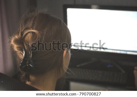Woman girl is working on computer with blank monitor screen with copy space. Blurred photo from back view.