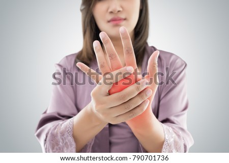 Asian woman holding her hand against gray background , Pain concept