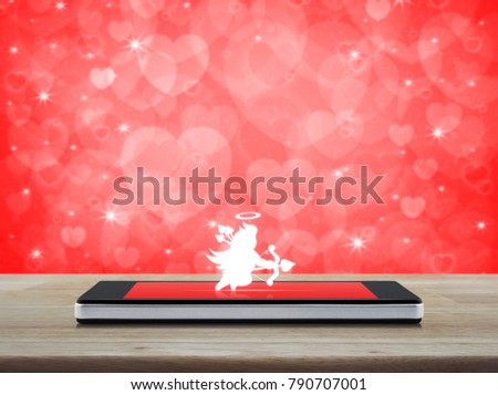 Cupid icon on modern smartphone screen on wooden table over blur red heart background, Internet love online, Valentines day concept