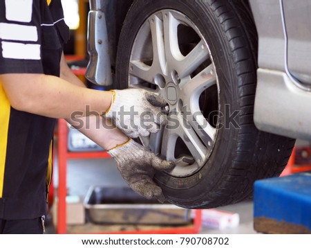  Male mechanic repairing car's wheel in workshop station . Royalty-Free Stock Photo #790708702