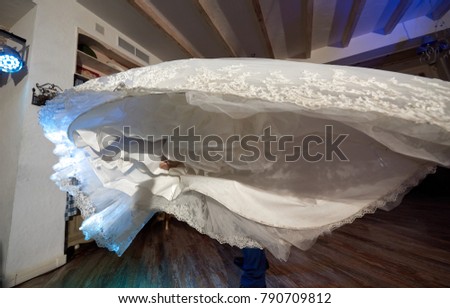 Wedding dress skirt of bride in hands of groom