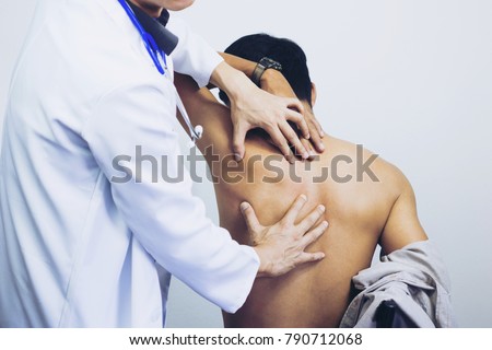 Side view close-up of a male physiotherapist examining mans back in the medical office. Doctor and patient man with a back pain. Royalty-Free Stock Photo #790712068