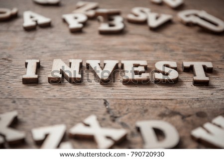 concept word with wooden letters alphabet on wooden table background - Invest