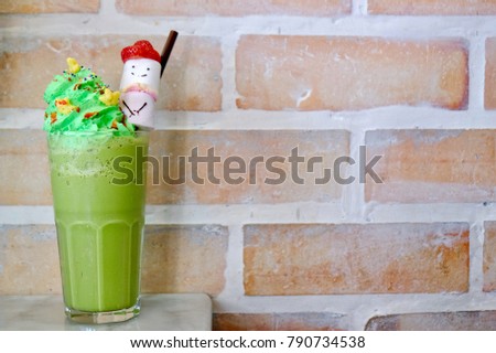 Green tea frappe in glass place on white table and in front of old brick wall with space for your text and design. Concept for Christmas day and coffee shop business. Blur picture. Vintage style.