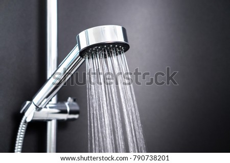 Water running from shower head in bathroom with dark black background. Simple stylish and modern Scandinavian home interior design. Royalty-Free Stock Photo #790738201