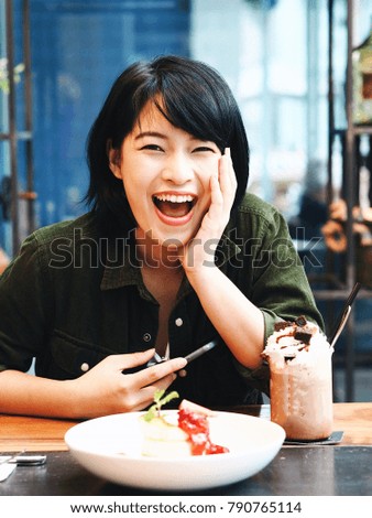 
Young Asian woman take a photo by smart phone and joyful with delicious pancake and dessert in coffee shop.