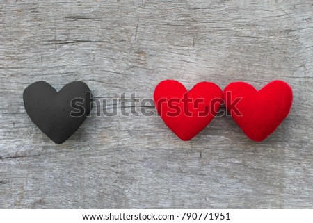 Coupple red heart and alone black heart put on wooden board. In concept bad valentine , third person, broken heart and adulterous.