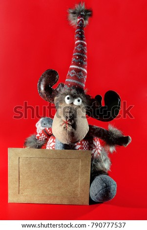 On a red background sits a toy moose in sweater . Next to it a sign for the congratulations.