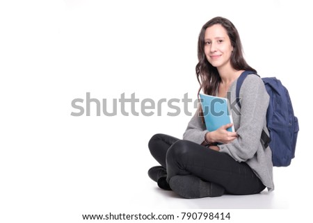 female student smiling and sitting holding colorful books with a backpack on a white background