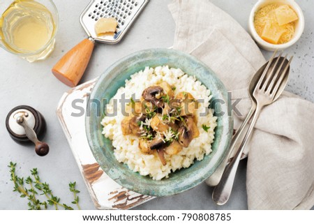 Risotto with chicken and mushrooms, thyme, garlic, parmesan cheese on old gray concrete background. Traditional Italian dish. Selective focus. Rustic style. Top view.