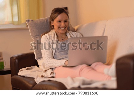 Smiling woman relaxing in the living room  and surfing the Internet on a computer.