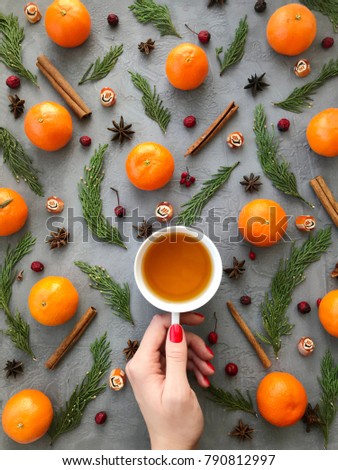 Winter background. Fashion Instagram composition with fir branches, cinnamon, mandarins and woman hand holding cup of tea. Flat lay, top view.