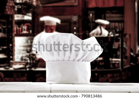 White cook hat on white wooden table and kitchen background with cook chef. 