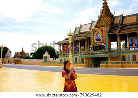 Fair-haired girl in sunglasses is standing on the main square of Phnom Penh against the background of the royal palace Royalty-Free Stock Photo #790829482