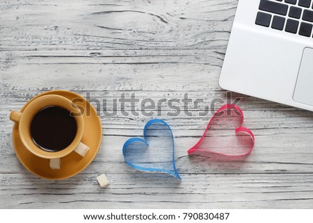 Background of a valentine on a wooden table with a laptop cup of coffee hearts beside a napkin for writing. Valentine's Day.