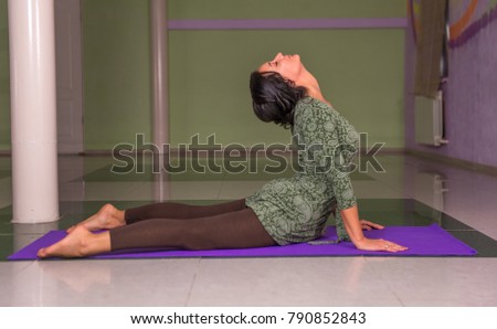 Professional yoga trainer doing yoga asana in fitness class