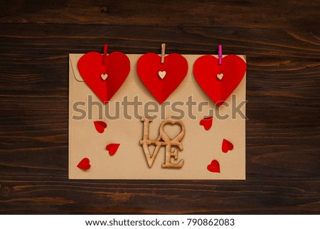 light envelope with hearts on clothespins  on a wooden background, the concept of Valentine's Day, top view