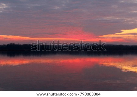 Red sunset with a symmetrical reflection in the water.                      
